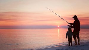 Angler surf fishing with his son using a spinning fishing rod